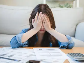 Person reviewing debt and credit card bills with a concerned expression